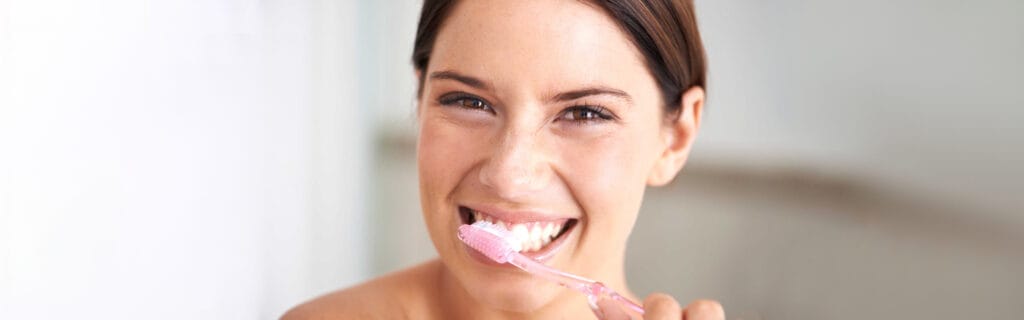 Smiling woman brushing her teeth for a whiter smile