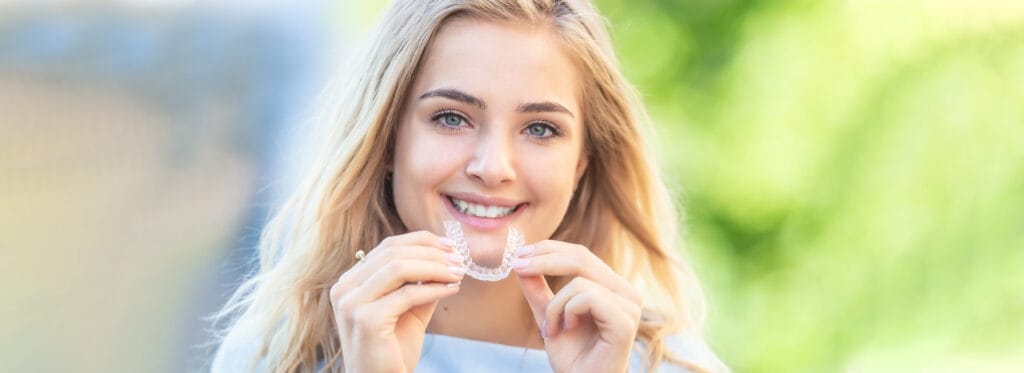 Smiling woman holding clear braces