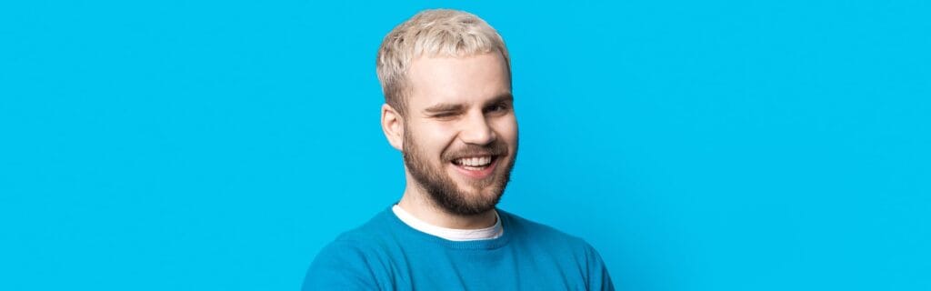 Smiling man winking against a bright blue background