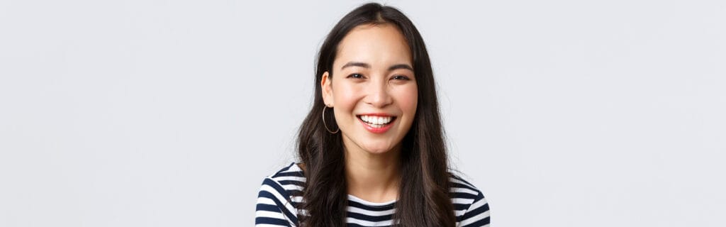 A woman in a black t-shirt smiling confidently with bright teeth